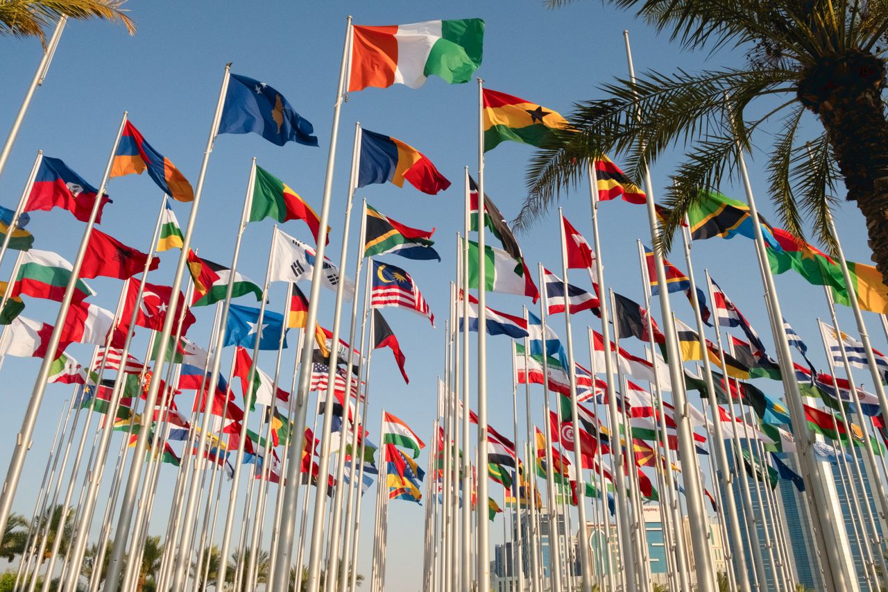 Vibrant display of international flags near Doha's skyline, symbolizing global unity.
